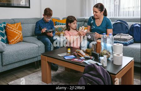 Mother preparing emergency backpack with her children Stock Photo