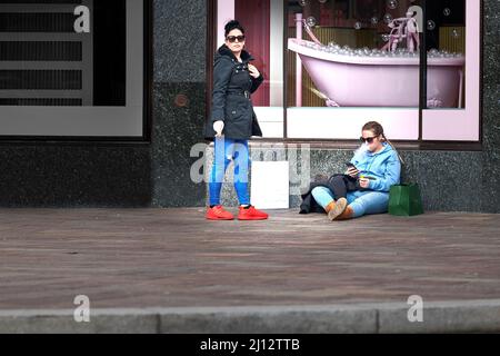 A couple of female shoppers take a cigarette smoking break outside the expensive and luxury good shop of Harrods, Kensington, London, England. Stock Photo