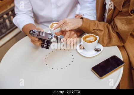 Close-up of male hands holding photocamera over table Stock Photo