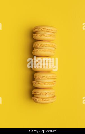 Sweet yellow macarons. Traditional french macaroons. Tasty dessert on yellow background. Top view. Stock Photo