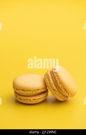 Sweet yellow macarons. Traditional french macaroons. Tasty dessert on yellow background. Stock Photo