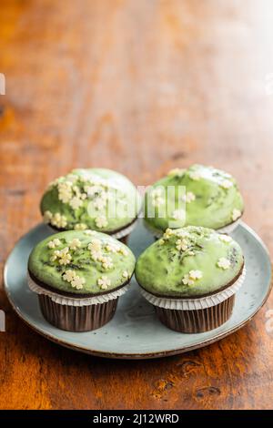 Sweet muffins with pistachio icing. Sweet dessert on the wooden table. Stock Photo