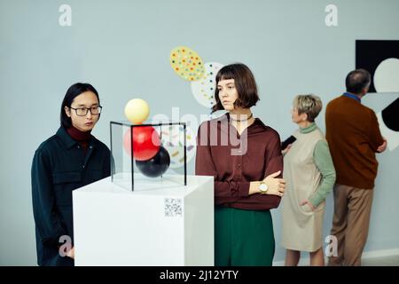 Group of modern senior and young people visiting exhibition in art gallery looking at various contemporary art objects and paintings Stock Photo