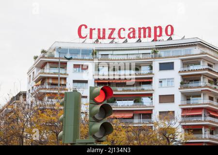 Seville, Spain. March, 2022. Traffic light in red in front of a facade with a brand of famous spanish beer company on the top Stock Photo