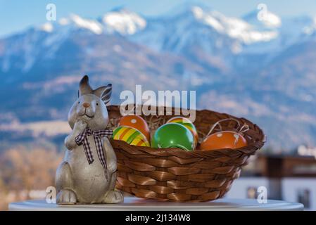 basket of colorful easter eggs with easter bunny and snowy tyrolean mountain landscape in the background Stock Photo