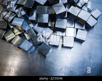 pile of small machined shiny steel cubes on metal surface Stock Photo