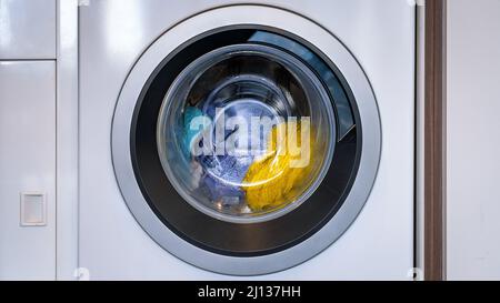Colorful laundry inside a front loader washing machine Stock Photo