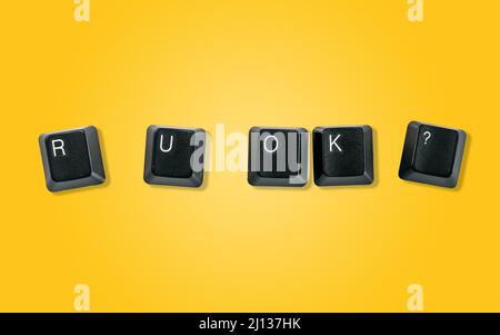 Computer keyboard keys spelling R U OK?, isolated on a yellow background Stock Photo