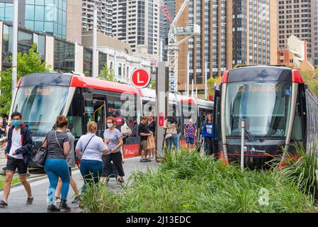 People moving, entering and leaving the light rail trams at Circular Quay, some wearing masks, on a Saturday in Sydney, New South Wales, Australia Stock Photo