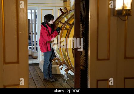 Student conservator Andrew Braund from West Dean College, cleans the helm of the Victorian battleship HMS Warrior at Portsmouth Historic Dockyard, as part of National Spring Cleaning Week. The conservation team have been researching and trialling a different way to treat the brass, using less abrasive techniques and a coating system that works well with the environment. Launched in 1860, HMS Warrior was Britain's first iron-hulled warship and had a lasting influence on naval architecture and design. Picture date: Tuesday March 22, 2022. Stock Photo