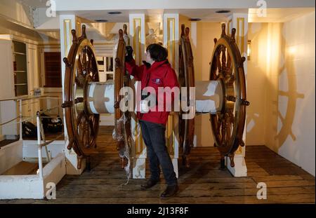 Student conservator Andrew Braund from West Dean College, cleans the helm of the Victorian battleship HMS Warrior at Portsmouth Historic Dockyard, as part of National Spring Cleaning Week. The conservation team have been researching and trialling a different way to treat the brass, using less abrasive techniques and a coating system that works well with the environment. Launched in 1860, HMS Warrior was Britain's first iron-hulled warship and had a lasting influence on naval architecture and design. Picture date: Tuesday March 22, 2022. Stock Photo