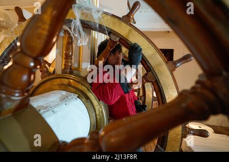 Student conservator Andrew Braund from West Dean College, cleans the helm of the Victorian battleship HMS Warrior at Portsmouth Historic Dockyard, as part of National Spring Cleaning Week. The conservation team have been researching and trialling a different way to treat the brass, using less abrasive techniques and a coating system that works well with the environment. Launched in 1860, HMS Warrior was Britain's first iron-hulled warship and had a lasting influence on naval architecture and design. Picture date: Tuesday March 22, 2022. Stock Photo