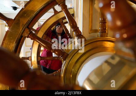 Student conservator Andrew Braund from West Dean College, cleans the helm of the Victorian battleship HMS Warrior at Portsmouth Historic Dockyard, as part of National Spring Cleaning Week. The conservation team have been researching and trialling a different way to treat the brass, using less abrasive techniques and a coating system that works well with the environment. Launched in 1860, HMS Warrior was Britain's first iron-hulled warship and had a lasting influence on naval architecture and design. Picture date: Tuesday March 22, 2022. Stock Photo