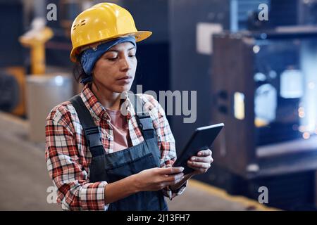 Young serious female manager of quality control using digital tablet to check information about goods in distribution warehouse Stock Photo