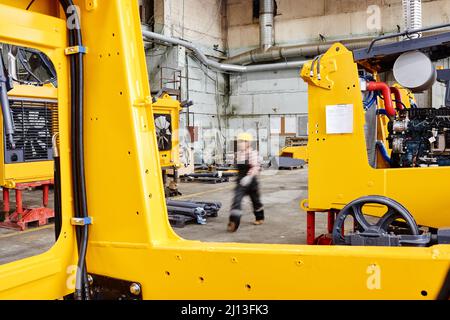 Blurry outline of female worker of industrial plant moving along huge working machines while walking from one workshop to another Stock Photo