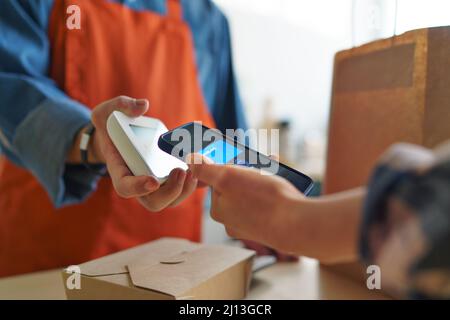 Close-up of waiter taking contactless smartphone payment from costumer in take away restaurant. Stock Photo