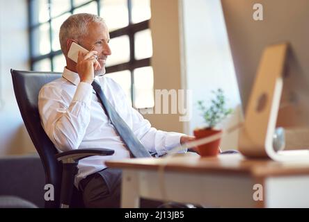 Hes the man everybody wants to talk to. Shot of a mature businessman using his phone in the office. Stock Photo