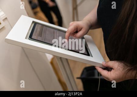 A woman checking in at a medical wellness spa using an electronic tablet to gather her personal data and sign medical waivers and forms Stock Photo