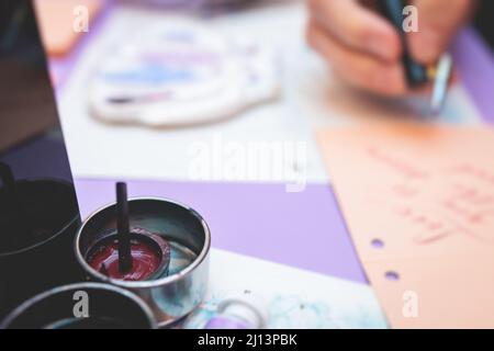 Process of calligraphy handwriting with an ink fountain pen feather, calligrapher practicing writing on postcard paper using pen brush and sign pen wi Stock Photo