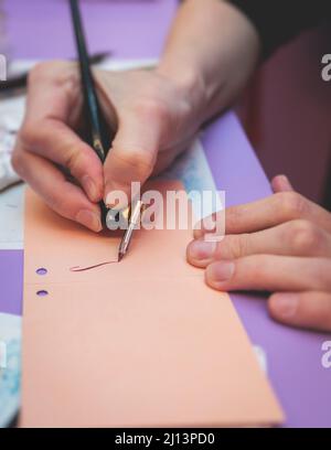 Process of calligraphy handwriting with an ink fountain pen feather, calligrapher practicing writing on postcard paper using pen brush and sign pen wi Stock Photo