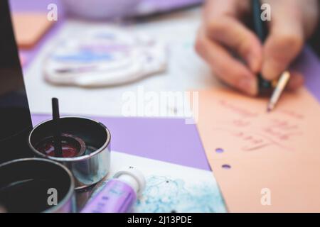 Process of calligraphy handwriting with an ink fountain pen feather, calligrapher practicing writing on postcard paper using pen brush and sign pen wi Stock Photo