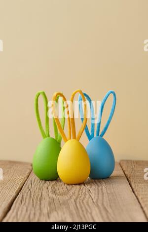 Colorful Easter eggs with bunny ears on beige background Stock Photo
