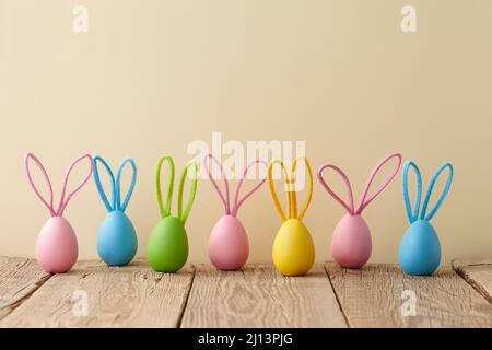 Colorful Easter eggs with bunny ears on beige background Stock Photo