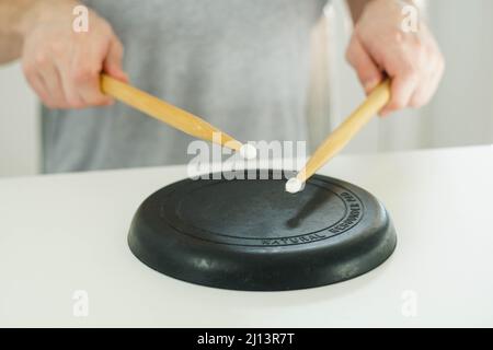 Close up of young drummer holding drum sticks and practicing on a black drum pad. Stock Photo