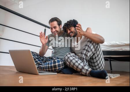 Cheerful biracial couple greeting someone via Skype Stock Photo