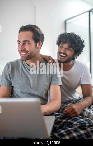 Cheerful gay couple sitting at the portable computer Stock Photo