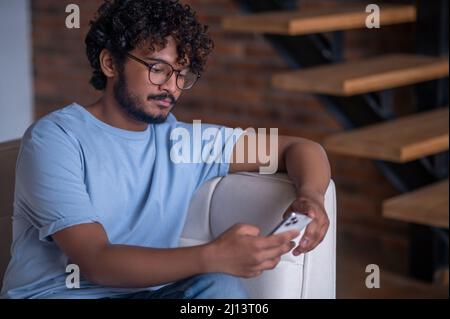 Tranquil concentrated guy looking at his cellphone screen Stock Photo