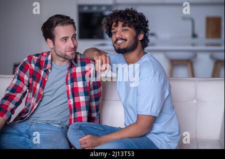 Romantic biracial gay couple sitting on the sofa Stock Photo