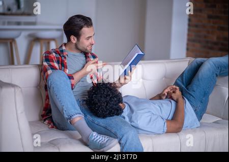 Concentrated guy sharing the contents of the book with his partner Stock Photo