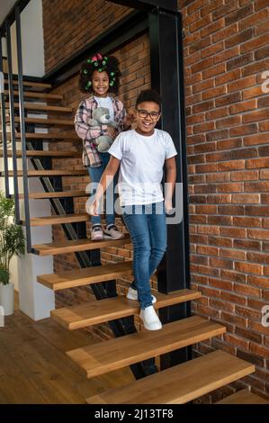 Boy and girl walking down stairs smiling at camera Stock Photo