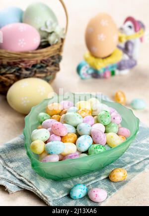 Bowl of easter candy and pastel colored eggs on a table Stock Photo