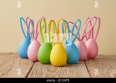 Colorful Easter eggs with bunny ears on beige background Stock Photo