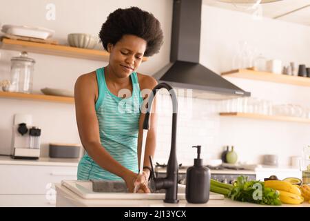 Mid adult african american woman washing hands while preparing food at home Stock Photo