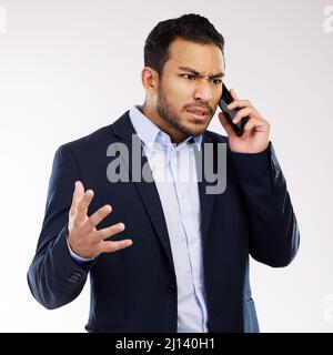 Dont make your problem my problem. Studio shot of a young businessman looking angry while talking on a cellphone against a white background. Stock Photo