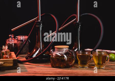 Tea in teapot, lime and hookahs on wooden surface isolated on black Stock Photo