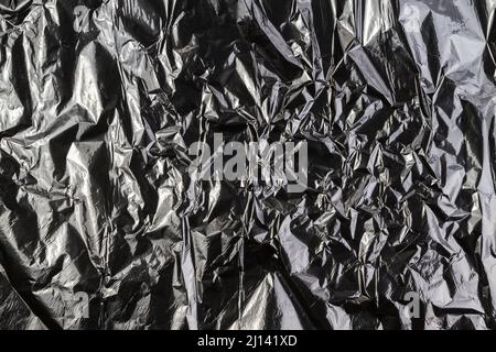 Black dark silver crumpled plastic material texture background Stock Photo