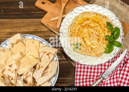 Aerial view of a plate of homemade hummus with pita bread and crackers. Fresh, healthy and natural food concept. Stock Photo