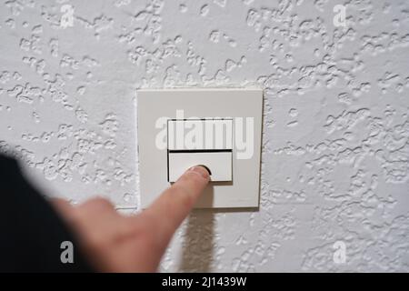 Hand turning off the light on a switch Stock Photo