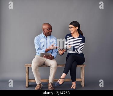 Im glad that youre finally connected. Shot of two colleagues sitting next to each other while using digital tablets. Stock Photo