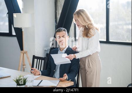 Blonde woman showing na document to her boss Stock Photo