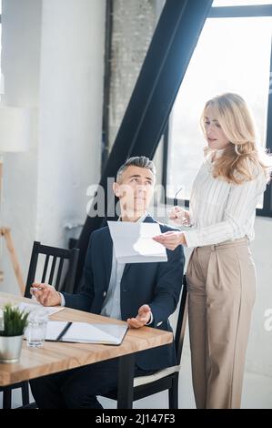 Blonde woman showing na document to her boss Stock Photo