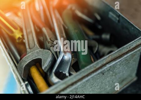 Metal box with set of wrenches and screwdrivers close-up. Working tool of locksmith or mechanic. Sunlight glare. Background. Stock Photo