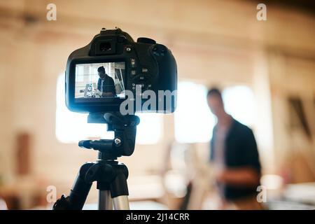 Hes all set to get the tutorial under way. Shot of young carpenter recording a tutorial of him making a wooden masterpiece on a video camera inside Stock Photo