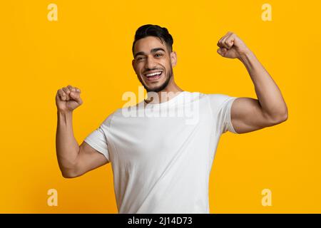 Cheerful athletic middle eastern man showing his muscles Stock Photo
