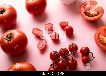 High angle view of fresh tomatoes and cherry tomatoes on pink background Stock Photo