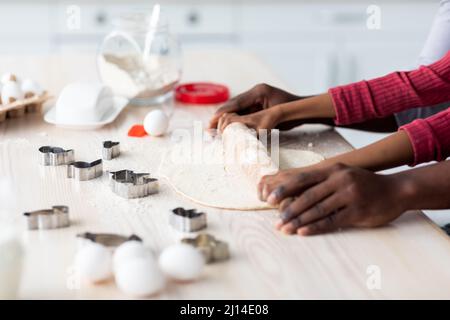 Unrecognizable african american man and child rolling pastry dough Stock Photo